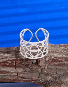 Dettaglio di un anello in argento con trama geometrica traforata su base naturale