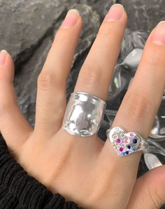 Detail of wide hammered silver ring paired with a multi-color gemstone heart ring