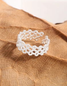 Detailed macro view of S925 sterling silver woven lace pattern ring on a textured leaf