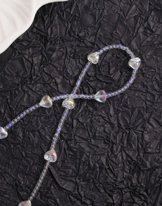 Macro shot of iridescent heart-shaped crystal beads on a textured black background
