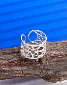 Dettaglio dell'anello in argento S925 traforato con motivo geometrico su legno naturale