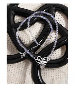 Detail of S925 silver necklace with sparkling bow and heart-shaped moonstone pendant