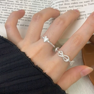 Matte silver heart ring and infinity twist band on a finger in retro style