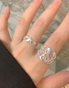 Détail des bagues en argent S925 à maille évidée et motifs de cœur sur les doigts