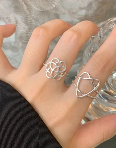 Detail of silver hollow floral and geometric triangular rings set worn on finger
