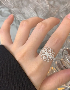 Detailed close-up of a silver hollow flower ring with laser-cut petals on a finger