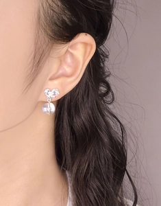 Gros plan d'une boucle d'oreille nœud en argent S925 avec zircon et perle translucide