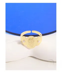 Détail d'une bague fraise dorée avec perles sur fond bleu et anneau ajustable