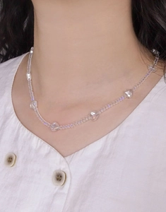 Macro detail of iridescent crystal heart beads and round pearls on a silver necklace