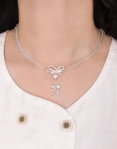 Close-up of double layer S925 silver necklace with crystal heart and bow on model neck