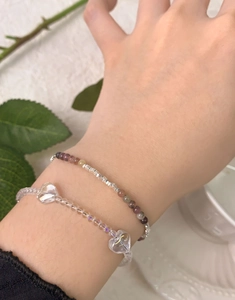 Detail of S925 silver heart charm and crystal beaded bracelet on woman's wrist