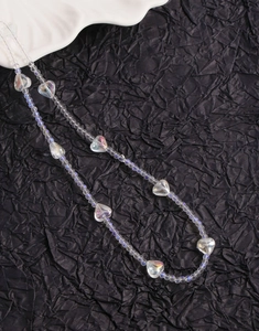 Close-up of iridescent heart crystal beads on a textured black background