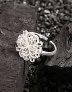 Detailed close-up of S925 sterling silver hollow flower ring on dark textured stones