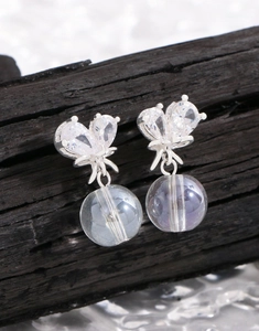 Gros plan de boucles d'oreilles papillon en argent avec zircone et perle suspendue