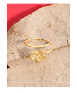 Macro view of a gold flower ring placed on a natural leaf showing fine metallic texture