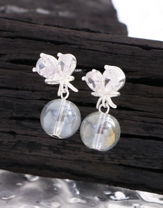 Vue macro des boucles d'oreilles nœud en argent S925 avec cristaux cœur et perles rondes