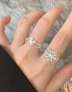 Macro shot of S925 sterling silver hollow flower ring and heart chain ring on finger