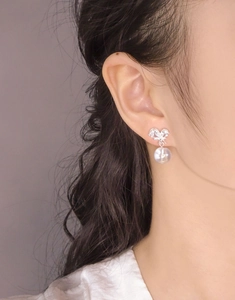 Détail de boucle d'oreille nœud en argent S925 avec zircon et perle sur modèle