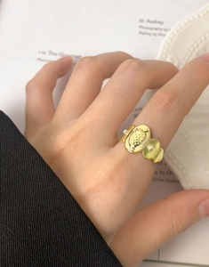 Détail d'une bague fraise plaquée or ornée de petites perles sur la main d'une femme