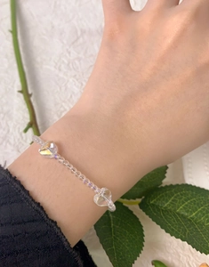 Detail of S925 silver beaded bracelet with iridescent crystal heart charms on wrist