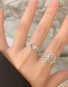 Close-up of S925 sterling silver hollow heart ring and Celtic knot ring on finger
