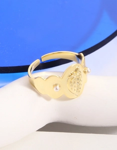 Gros plan sur bague fraise dorée aux bords ondulés et détails en perles blanches