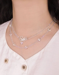 Detail of layered S925 silver necklace with translucent beads and a bow heart pendant