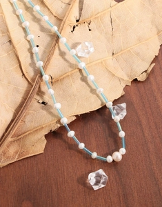 Détail de perles naturelles blanches et tubes bleus sur une feuille brune