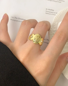 Vue détaillée d'une bague fraise plaquée or avec perles sur un doigt de femme