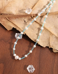 Détail du collier de perles naturelles avec tubes bleus sur une surface en bois rustique