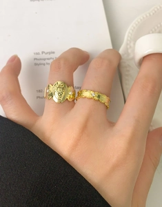 Détail d'une bague fraise dorée et d'un anneau fin serti d'un diamant portés à la main