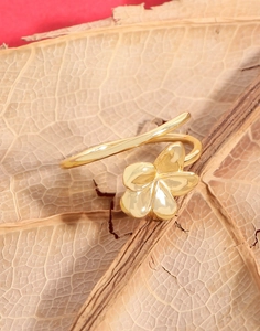 Close-up of golden flower ring with adjustable spiral band on natural leaves