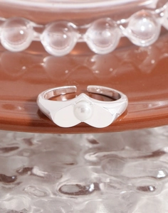 Macro detail of S925 silver heart ring with elegant pearl inlay and wavy band