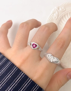 Detail of stacked S925 silver rings with heart-shaped pink ruby and zircon stones