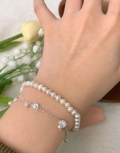 Détail d'un bracelet en argent S925 avec perles et breloque coquillage au poignet