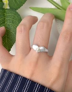 Detail shot of heart-shaped S925 silver ring with a white pearl on a model's finger