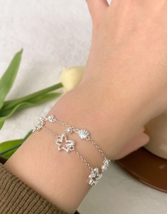 Détail d'un bracelet double couche argenté avec étoile coquillage et perle au poignet