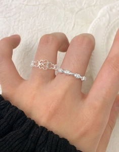 Close-up of heart-shaped hollow ring and beaded bamboo joint ring on woman's finger
