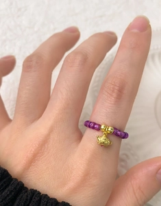 Détail de bague perlée en argent S925 avec cristaux violets et pendentif théière dorée