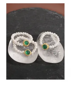 Close-up of S925 silver rings with natural pearls and green agate on black stone base