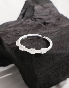 Macro shot of S925 sterling silver spiral ring on a textured black charcoal stone