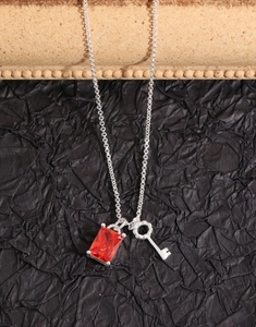 Macro view of S925 silver necklace featuring a red zircon rectangle and key charm