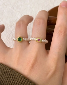 Close-up of S925 silver pearl rings set with green and pink gemstone details