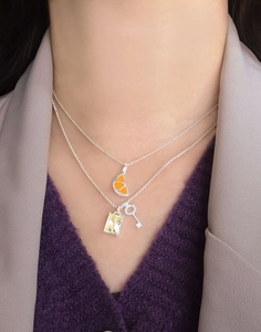 Detail of layered S925 silver necklace with citrus slice, yellow stone and key pendant