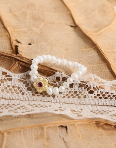 Détail de bague perles d'eau douce avec fleur dorée et zircon rouge sur dentelle