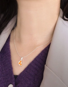 Close-up of S925 silver necklace with orange enamel heart pendant worn on model