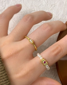 Detail of S925 silver ring set with natural freshwater pearls and a ruby style stone on a finger