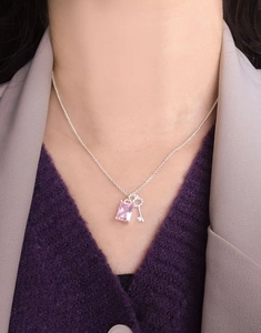 Detail of S925 silver necklace with pink sugar cube zircon and mini key pendant on model