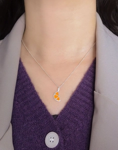 Detail of S925 silver necklace with orange slice pendant on purple sweater
