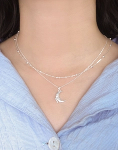 Close-up of layered S925 silver necklace featuring a textured crescent moon pendant
